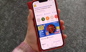 Dłoń trzymająca smartfon z aplikacją Lidl Plus, na ekranie widoczna promocja na kiełbasę.
