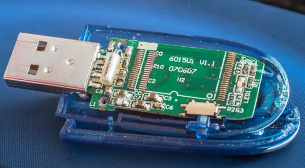 Rozłożony pendrive z widoczną zieloną płytką drukowaną i metalowym złączem USB.