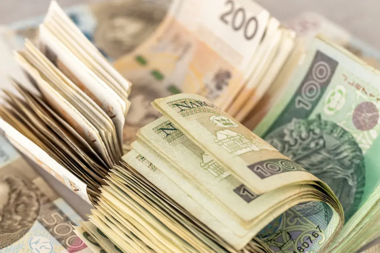 Stosy polskich banknotów o różnych nominałach, w tym 100 zł i 200 zł.